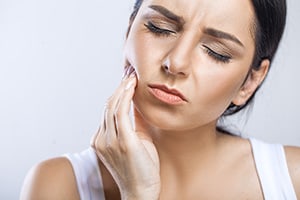 woman holding jaw in pain